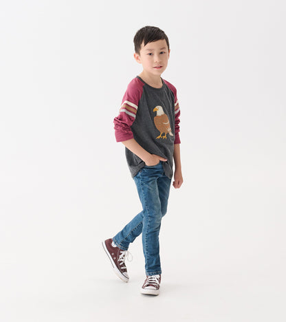 Gray long sleeve raglan t-shirt with maroon sleeves and eagle graphic, worn by a boy with blue jeans and sneakers.