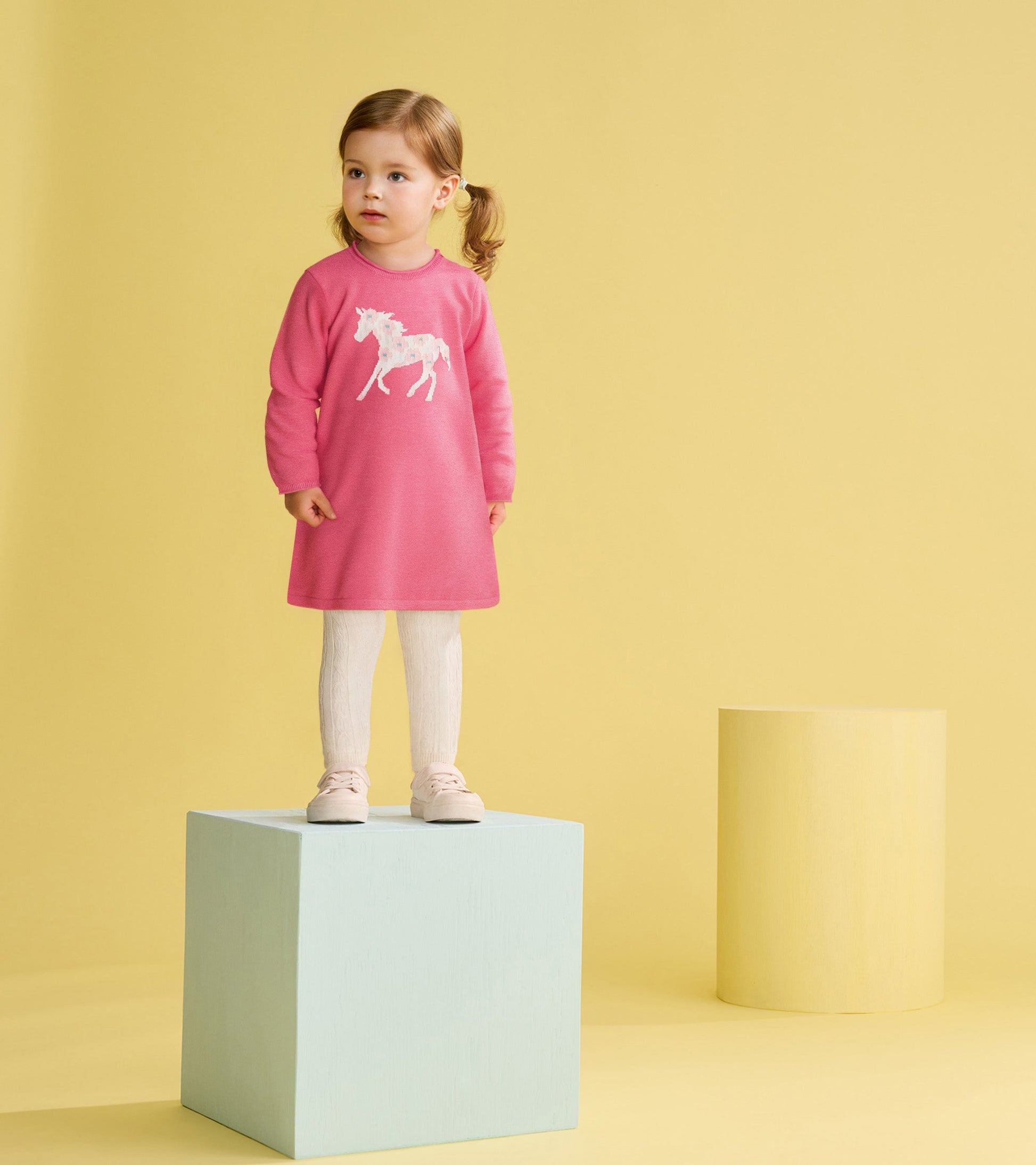 Pink sweater dress featuring a white horse design, paired with white textured leggings and light pink shoes.