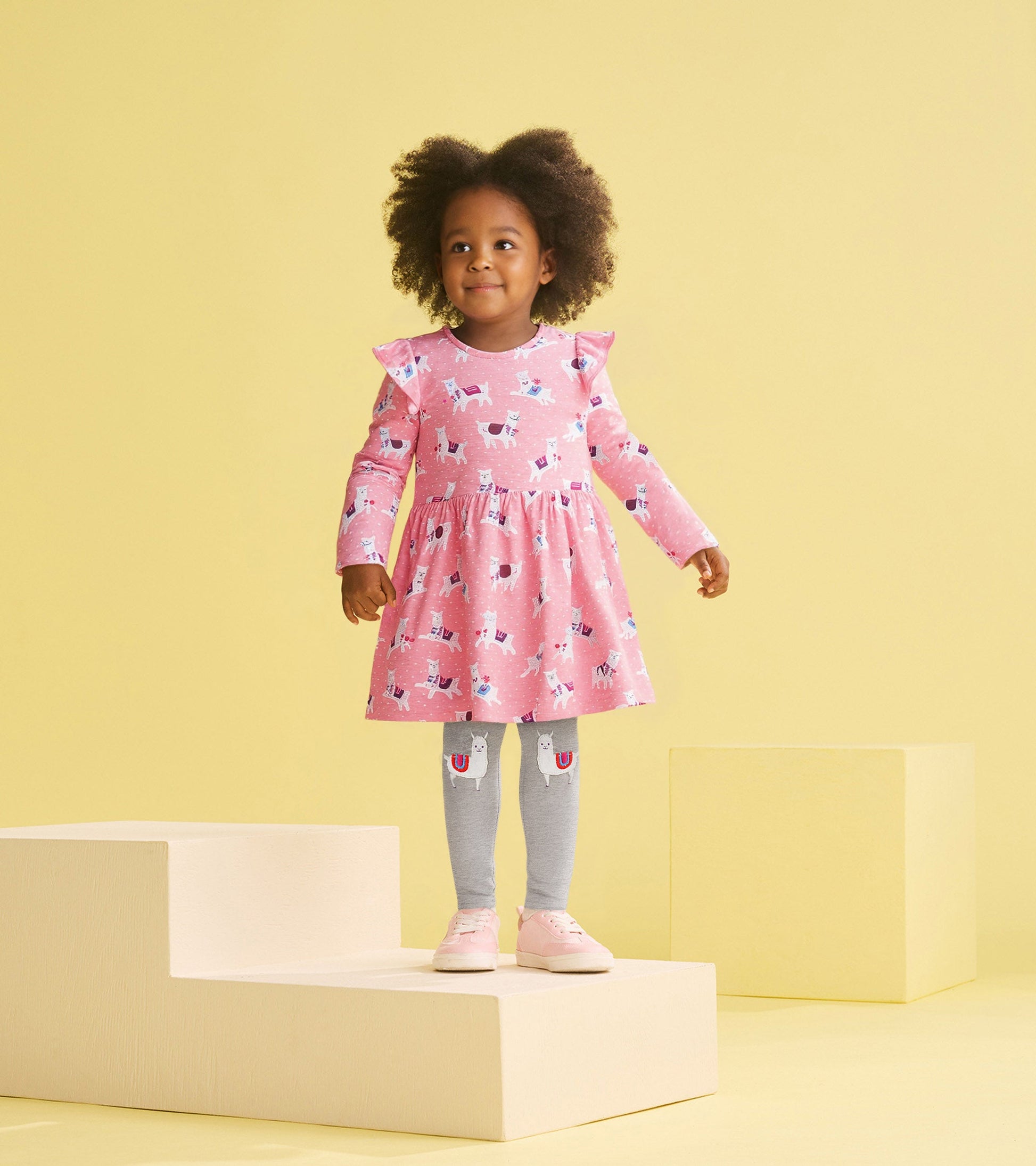 Pink dress with ruffle sleeves and alpaca print, paired with gray leggings featuring alpaca design, worn by a toddler.