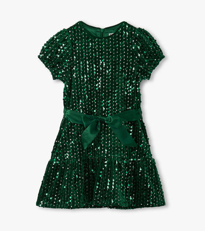 Green velvet dress adorned with sequins, featuring short puff sleeves and a ruffled hem, tied with a matching belt.