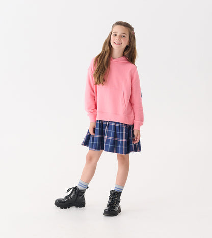 Pink hoodie paired with a navy plaid skirt, worn with black boots and striped socks.