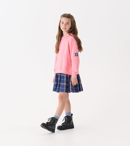Pink hoodie paired with a navy plaid skirt, worn with black boots and striped socks.