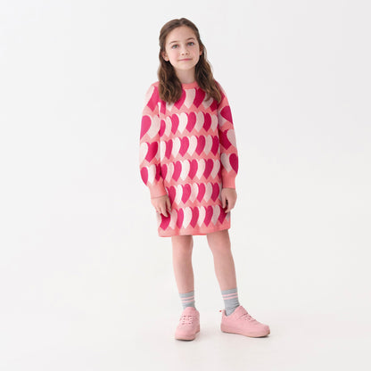 Pink sweater dress featuring a heart pattern, long sleeves, and a relaxed fit, worn with pink shoes and striped socks.