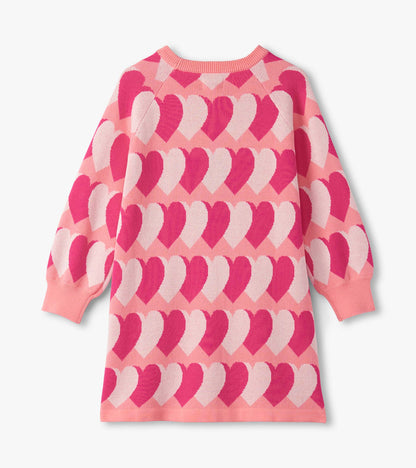 Pink sweater dress featuring a heart pattern in varying shades of pink, with long sleeves and a relaxed fit.