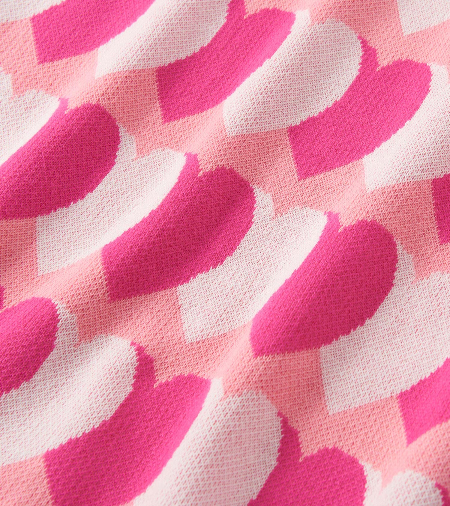 Pink sweater dress featuring a playful heart pattern in varying shades of pink and white. Soft, cozy knit material.