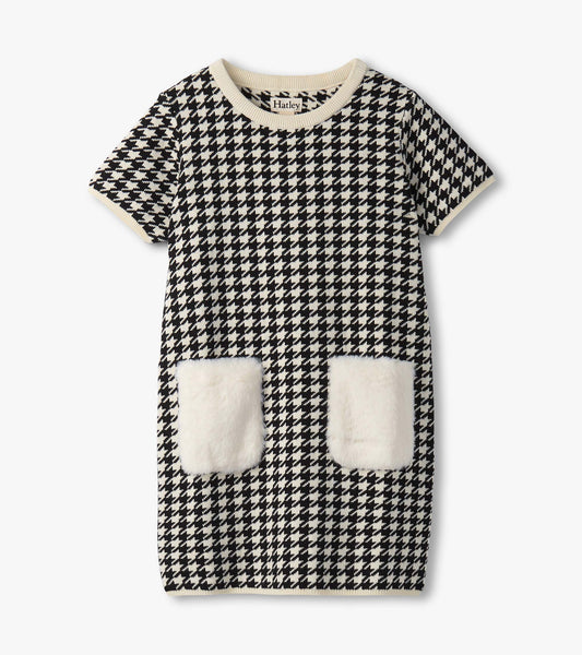 Black and white houndstooth sweater dress featuring faux fur pockets and a ribbed neckline. Short sleeves, casual style.