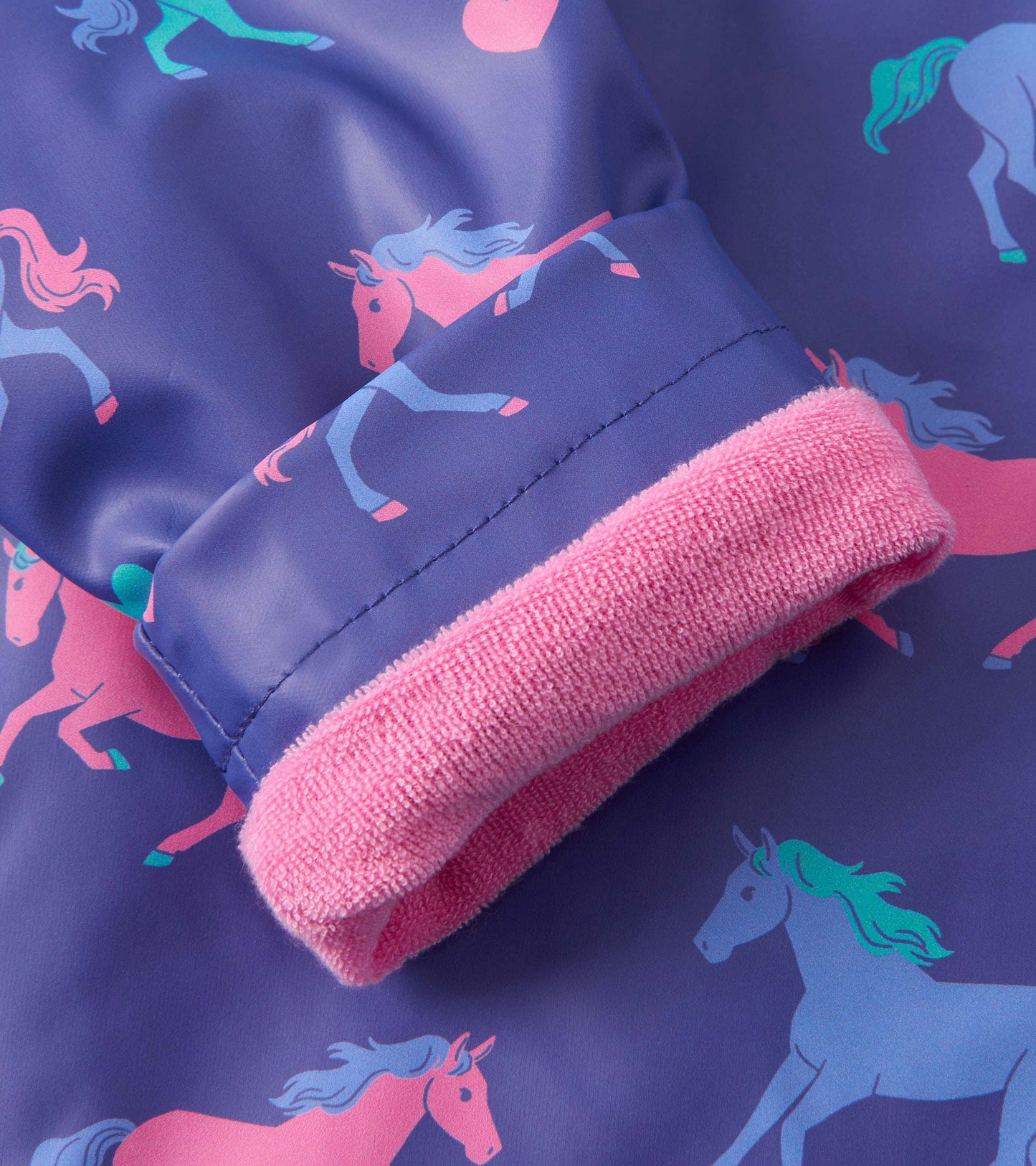 Purple raincoat featuring pink horse patterns and a soft pink cuff. Ideal for baby and toddler girls.