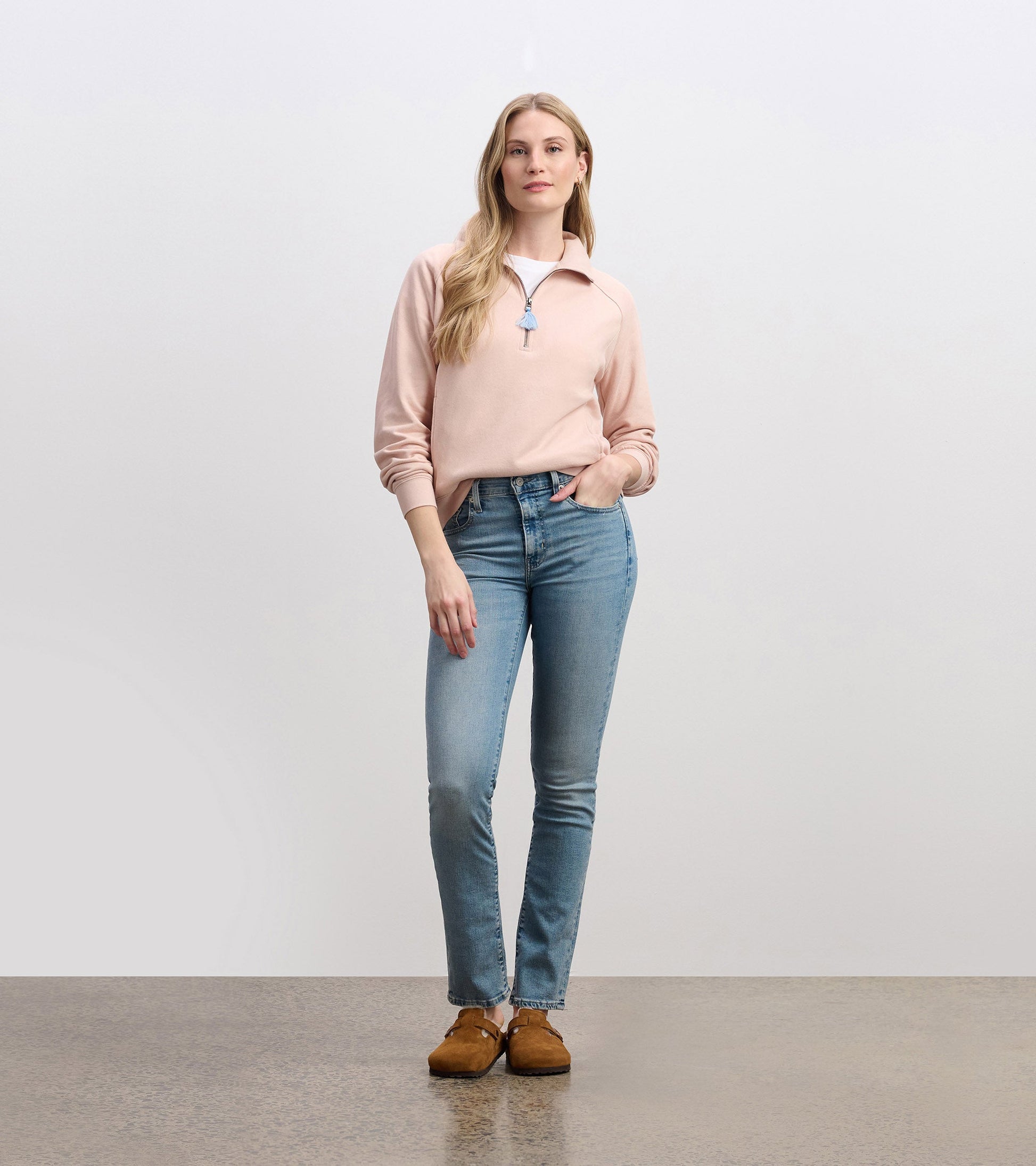 Pink mock neck pullover with a zip front, paired with light blue jeans and brown shoes, styled casually.