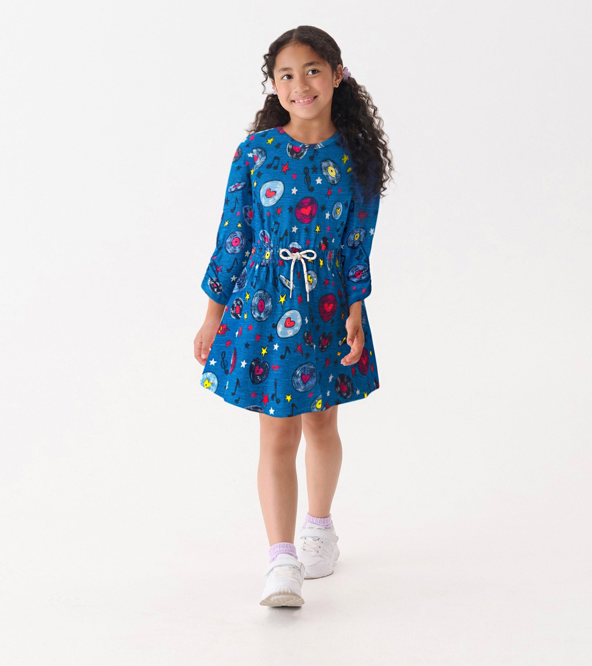 Blue cinched waist dress featuring music-themed patterns, long sleeves, and a drawstring detail. Suitable for casual wear.