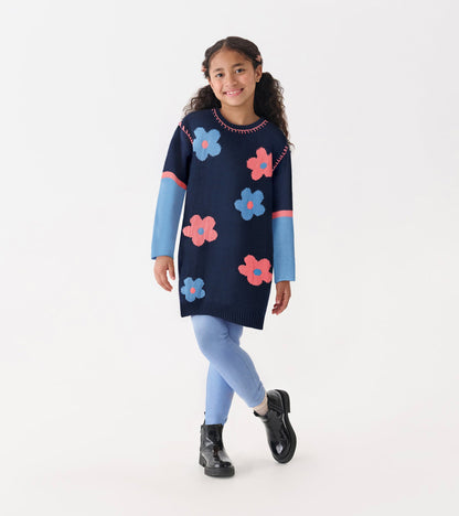 Navy sweater dress with colorful flower patterns, drop shoulder design, and long sleeves, paired with light blue leggings.