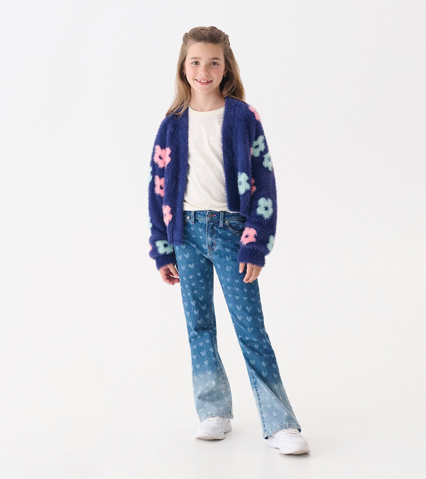 Navy open cardigan with big pink and mint flowers, worn over a white shirt and paired with flared jeans.