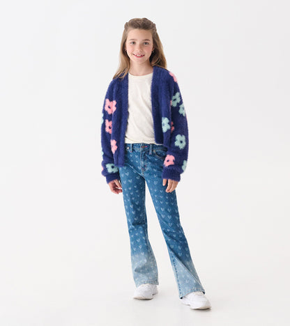 Navy open cardigan with big pink and mint flowers, worn over a white shirt and paired with flared jeans.