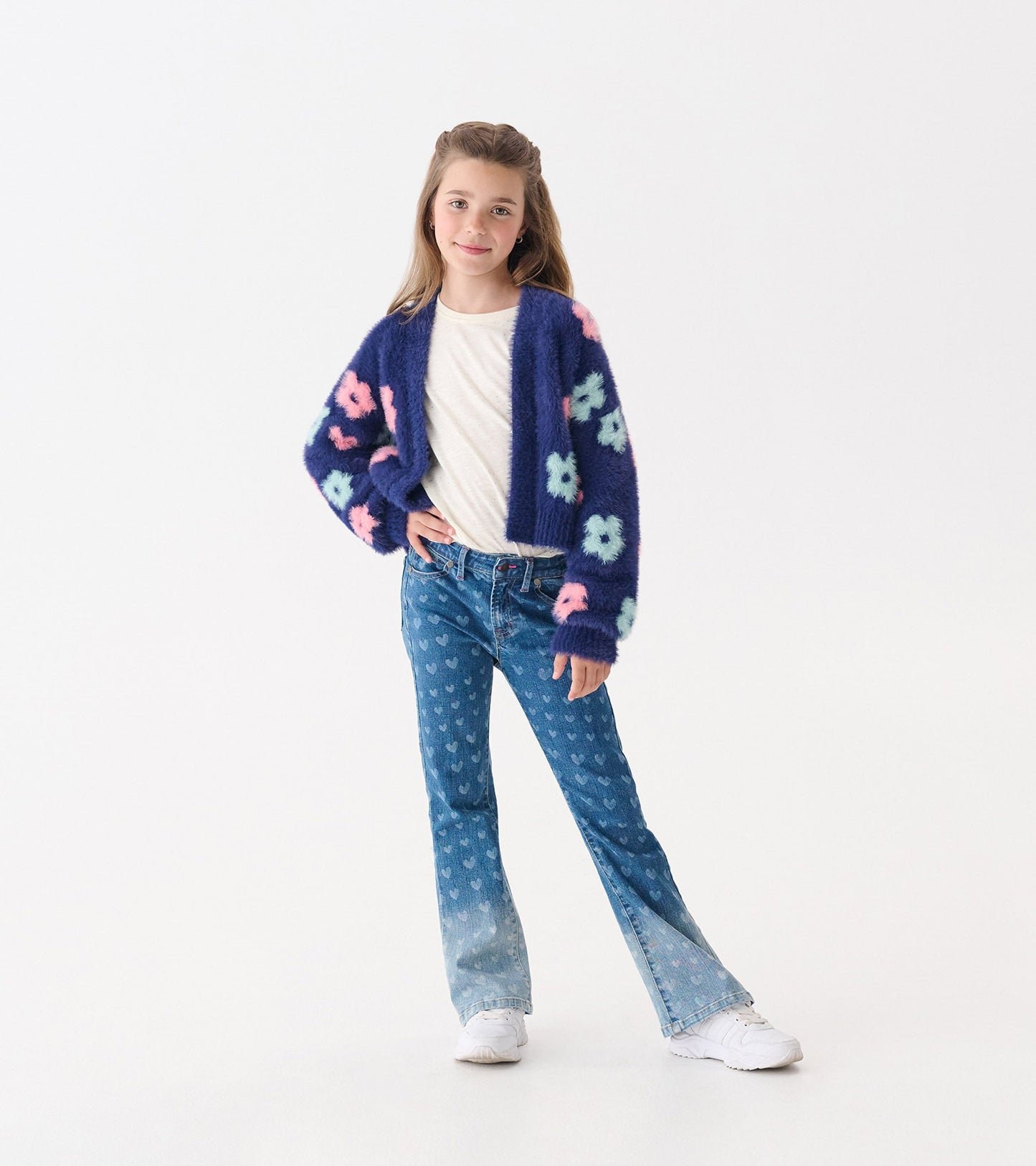 Navy open cardigan with large pink and blue flowers, worn over a white shirt and paired with flared jeans.