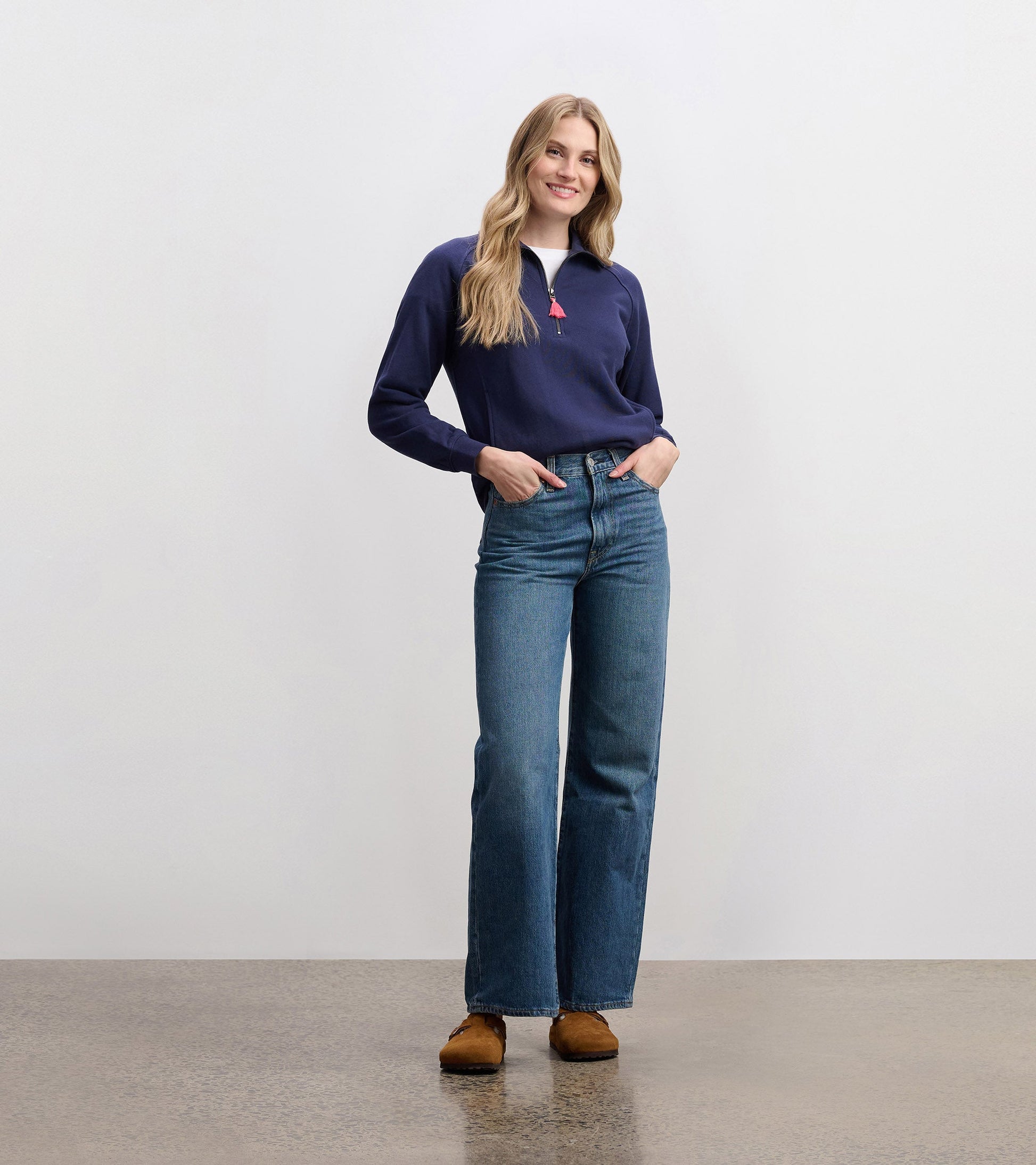 Mock neck pullover in patriot blue, featuring a zip closure and long sleeves, paired with high-waisted jeans.
