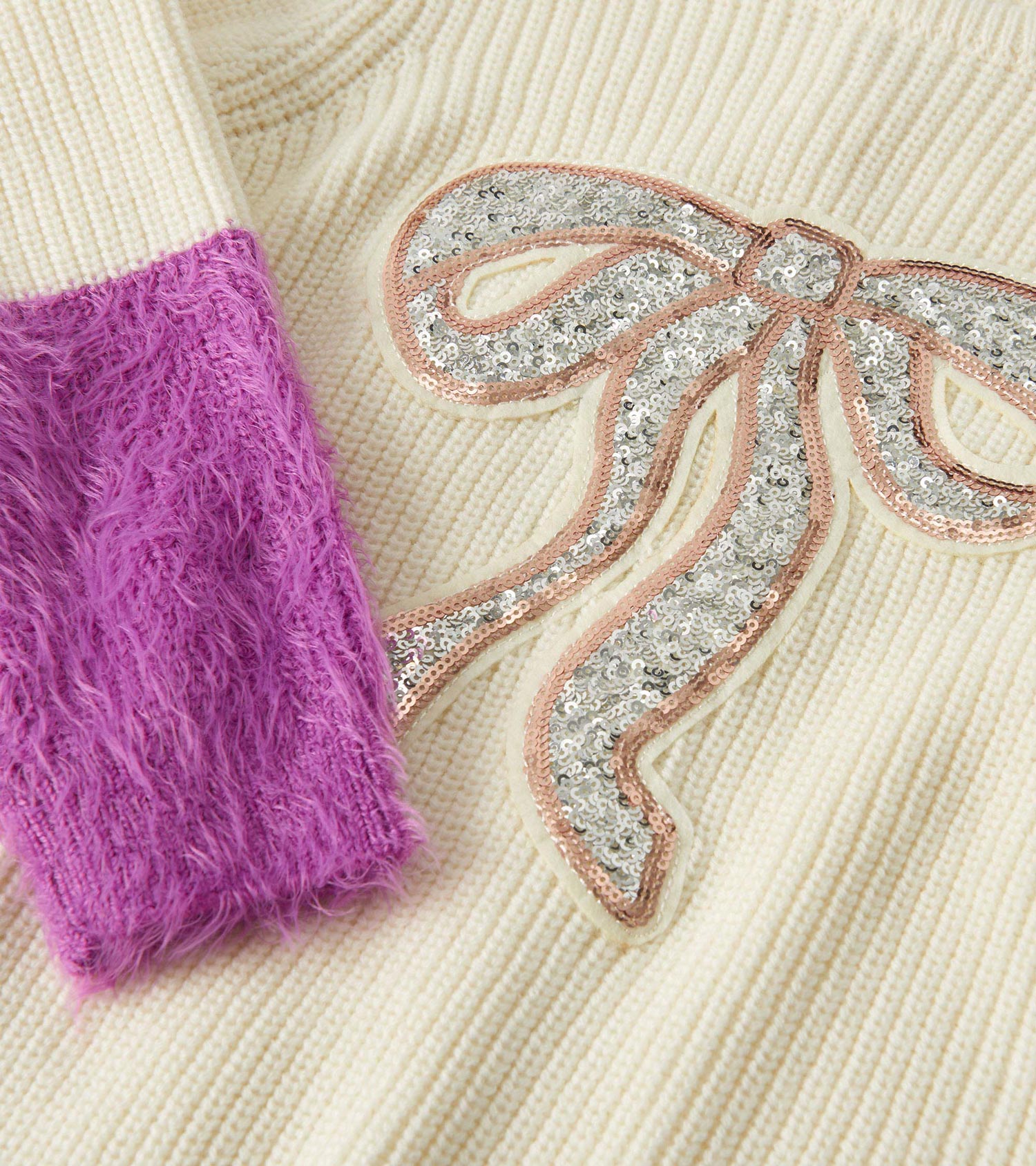 Cream sweater featuring fluffy purple sleeves and a sequined silver bow design.