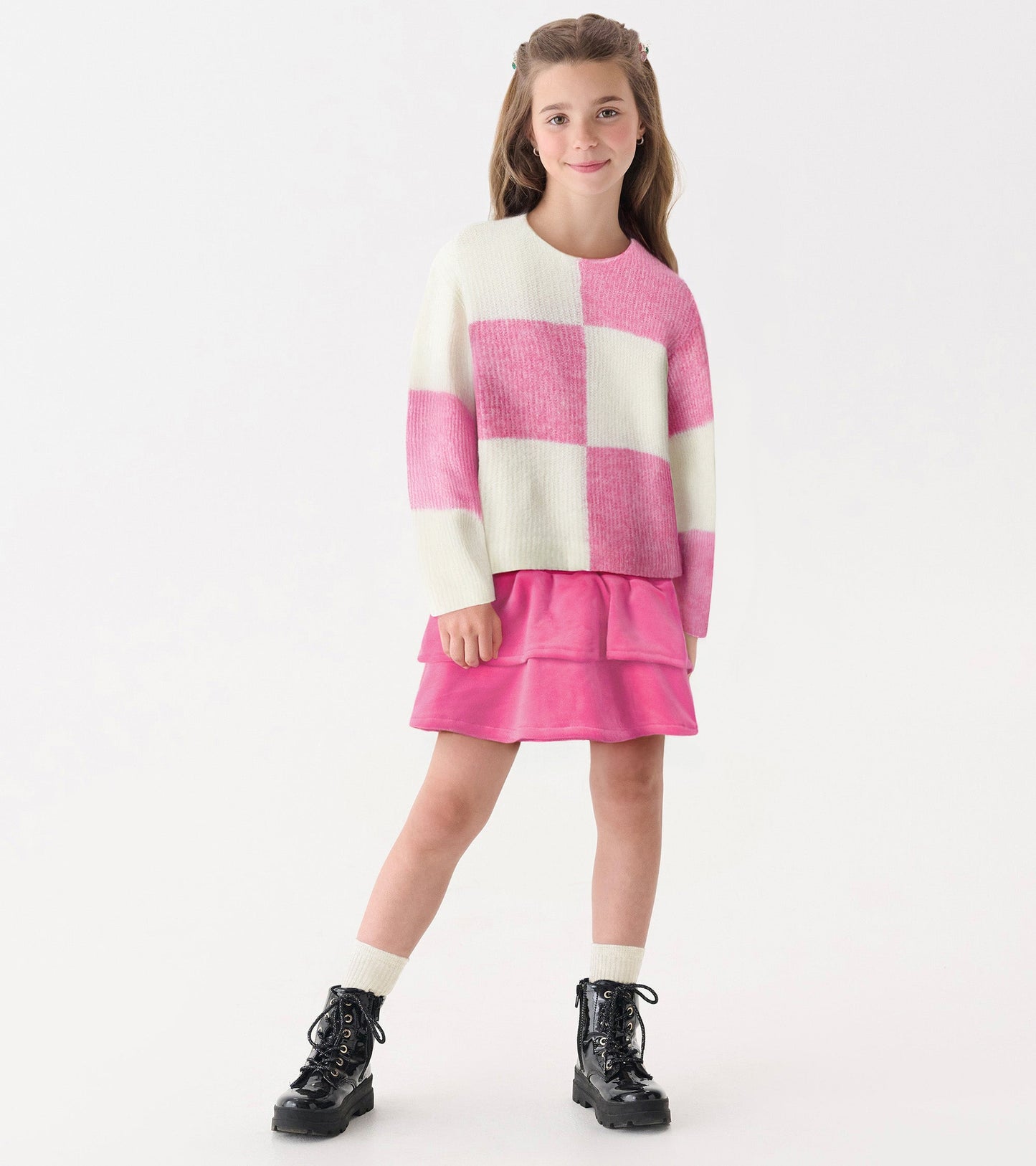 Pink and white check drop shoulder sweater with long sleeves, paired with a pink skirt and black boots.