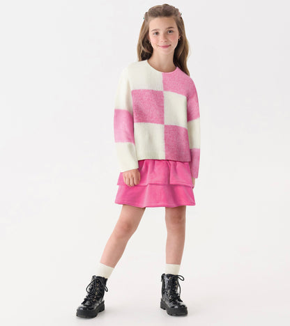 Pink and white check drop shoulder sweater with long sleeves, paired with a pink skirt and black boots.