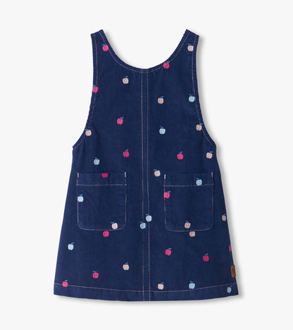 Front view of navy pinafore dress with embroidered pink, blue, and beige apples and two front patch pockets
