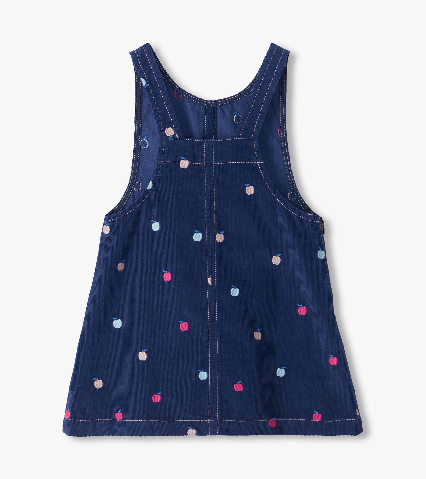 Back view of navy pinafore dress with cross-back straps and embroidered pink, blue, and beige apples