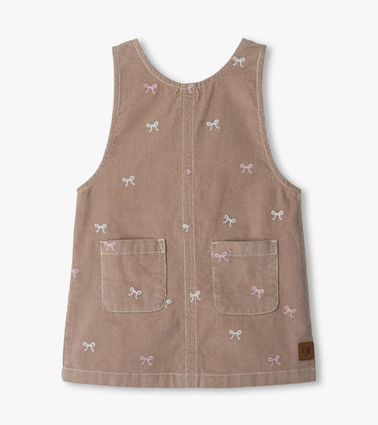 Front view of taupe pinafore dress with pink and white bow embroidery and two front patch pockets