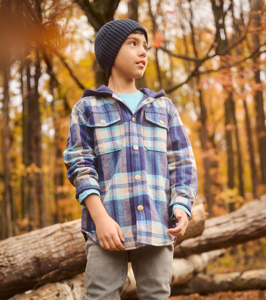 Boy wearing blue plaid snap-front hoodie shirt with chest pockets in a fall forest