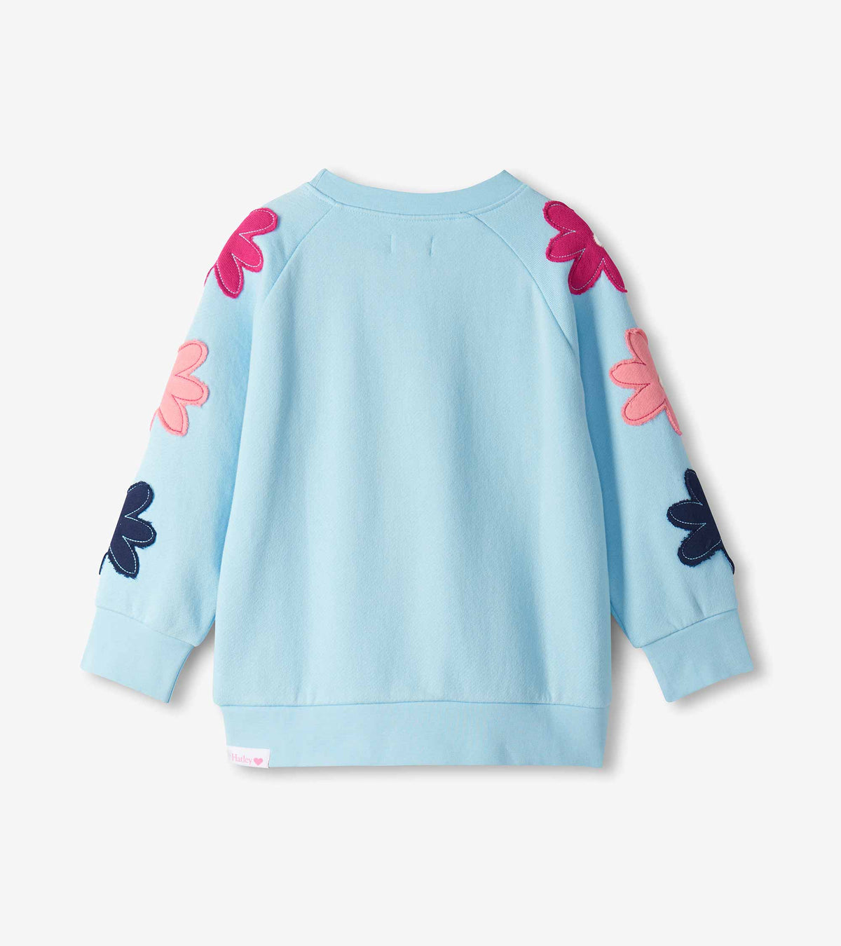 Back view of cool blue slouchy pullover with flower appliqués along both raglan sleeves