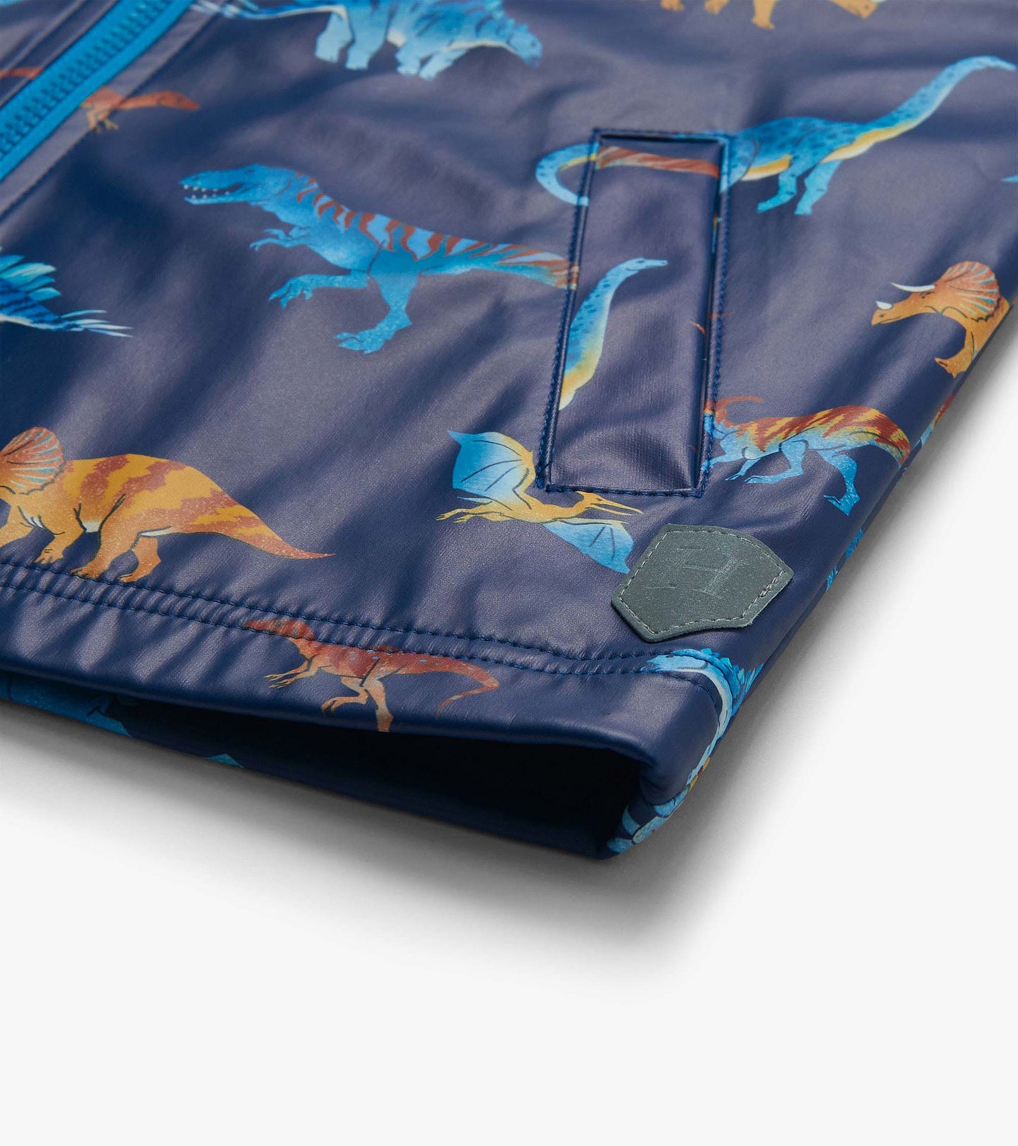 Close-up of front pocket and hem on navy rain coat with blue and orange dinosaur print