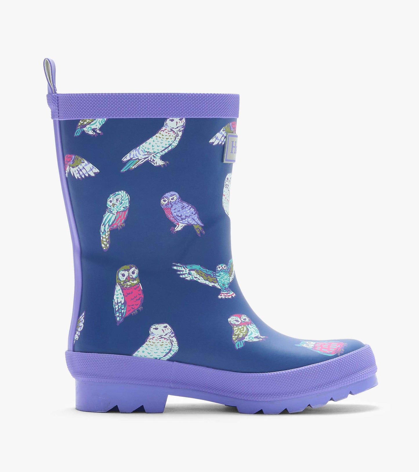 Side view of a navy rain boot with colorful owl print, purple trim, pull tab, and treaded sole