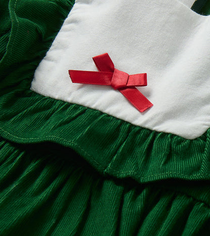 Close-up of red bow on white bib yoke with green ruffle trim and fine cord texture