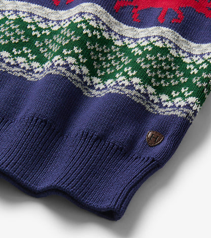 Close-up of sweater hem with green and white fair isle knit, navy ribbing, and small logo patch