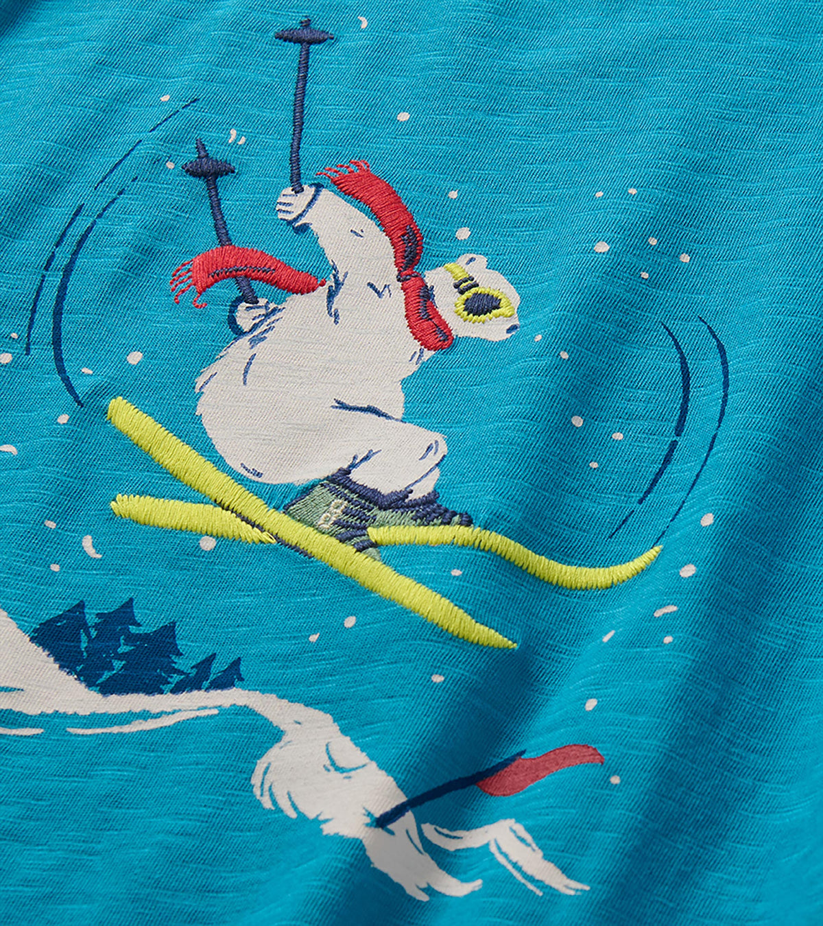 Close-up of embroidered skiing bear graphic with red scarf and yellow skis