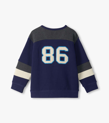 Back view of kids blue pullover top with dark gray yoke, cream sleeve stripes, and large 86 graphic