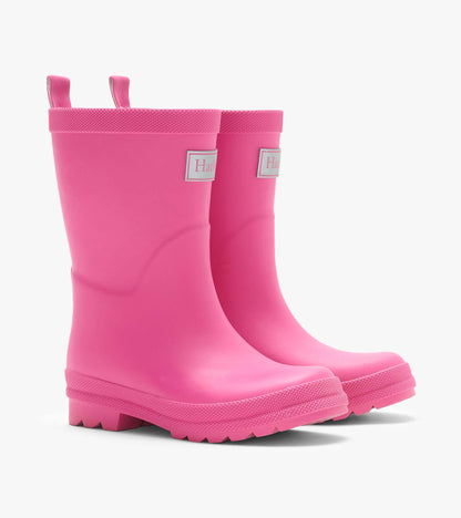 Pair of bright pink kids rain boots with pull tabs, side logo patch, and textured lug soles