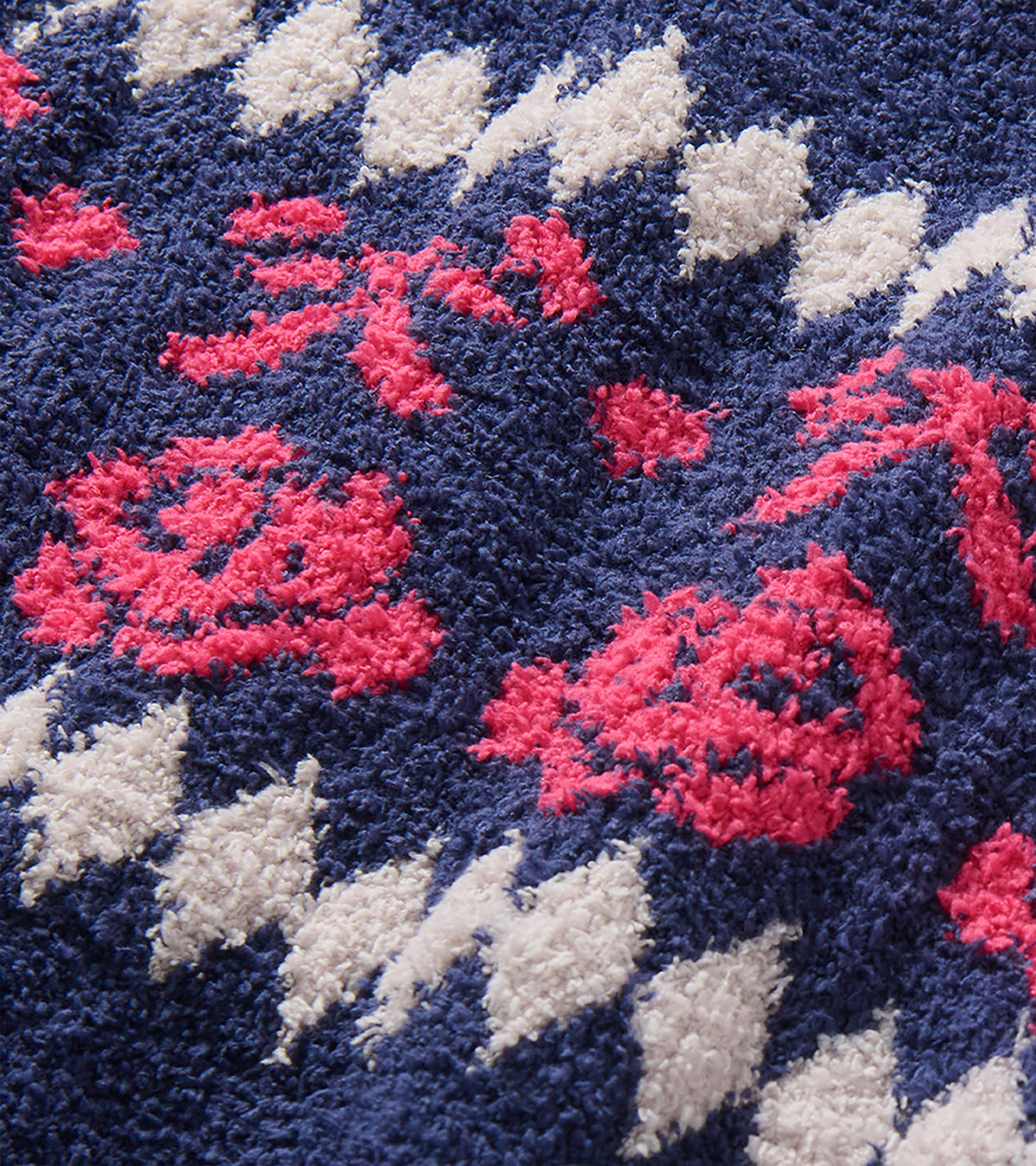 Close-up of navy sweater dress with pink rose and bow motif and white diamond pattern