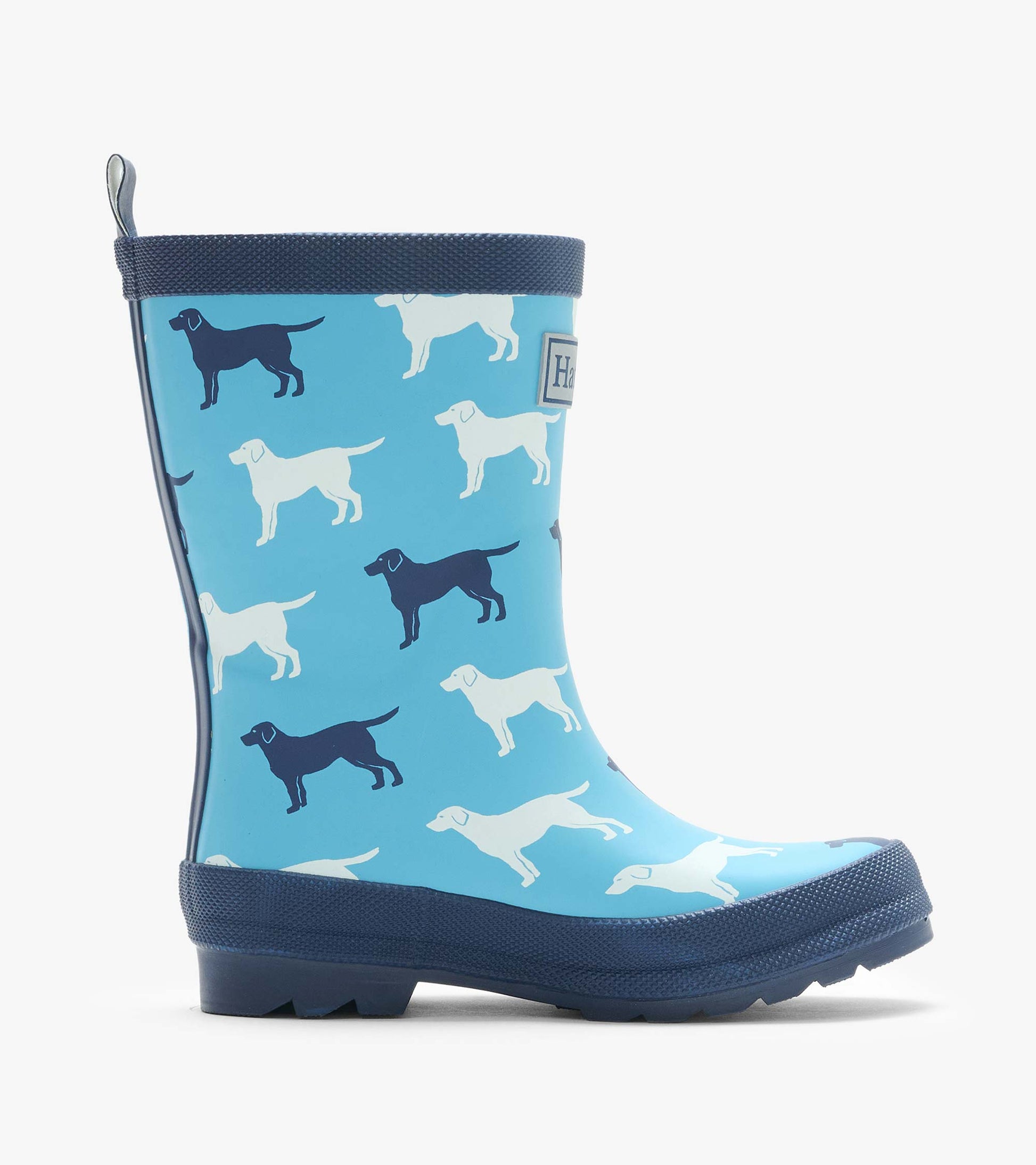 Side view of a blue kids rain boot with white and navy dog silhouettes and dark navy sole