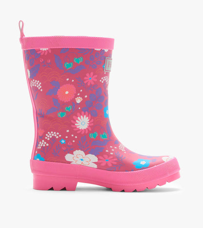 Side view of a pink kids rain boot with tiny floral print, textured trim, and lug sole