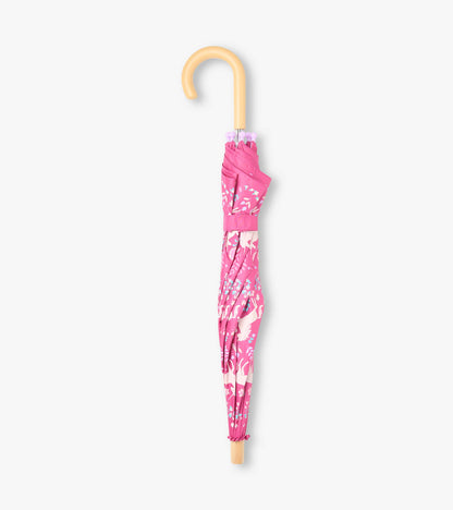 Closed pink unicorn print umbrella with curved light wood-look handle and matching wrap strap