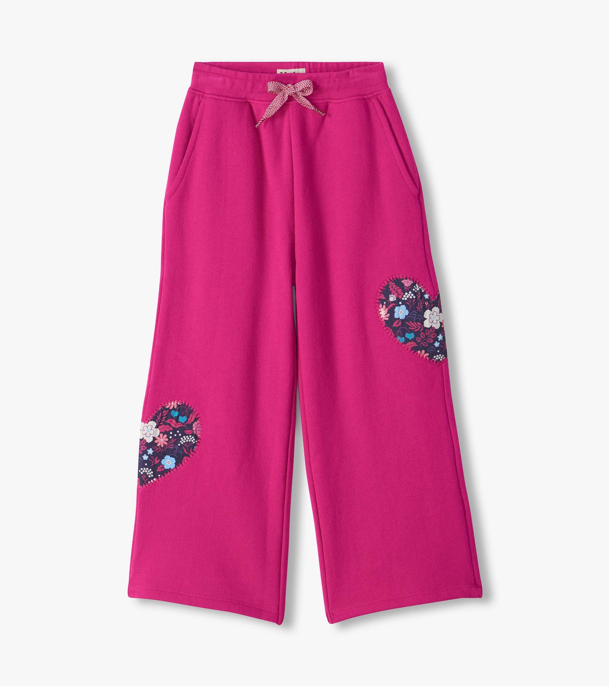 Bright pink wide leg track pants with drawstring waist, side pockets, and floral heart patches on the legs