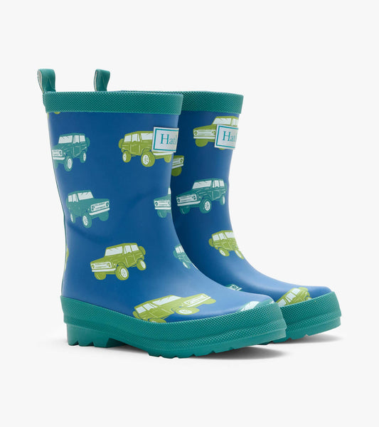 Pair of blue kids rain boots with green trim and vintage truck print, front angled view