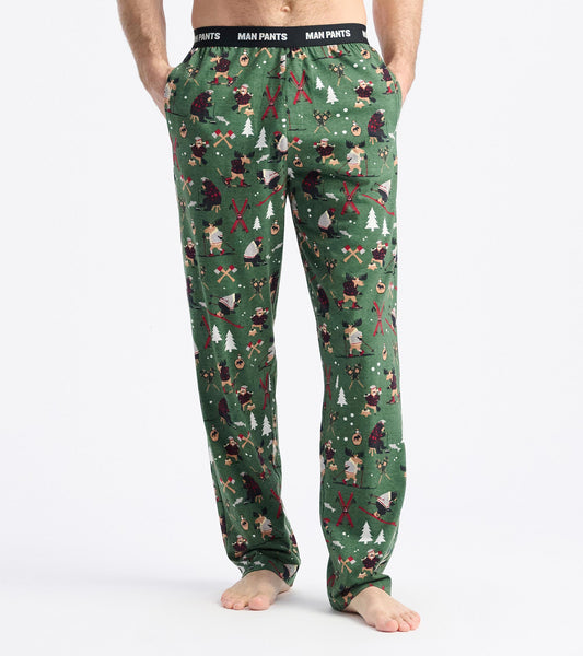 Green pajama pants featuring a winter-themed pattern with trees, bears, and outdoor activities. Elastic waistband for comfor…