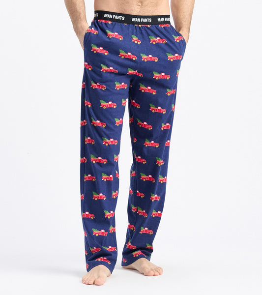 Navy pajama pants featuring a playful pattern of red trucks hauling Christmas trees. Elastic waistband for comfort.