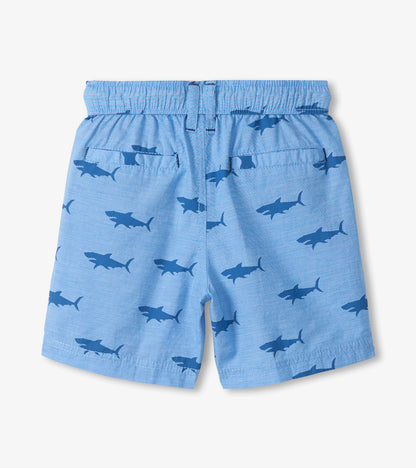 Light blue boys shorts with dark shark print, elastic waistband, and back pockets, front view