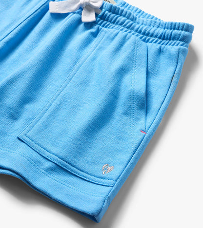 Light blue girls' shorts with elastic waistband, side pocket, and small embroidered logo detail