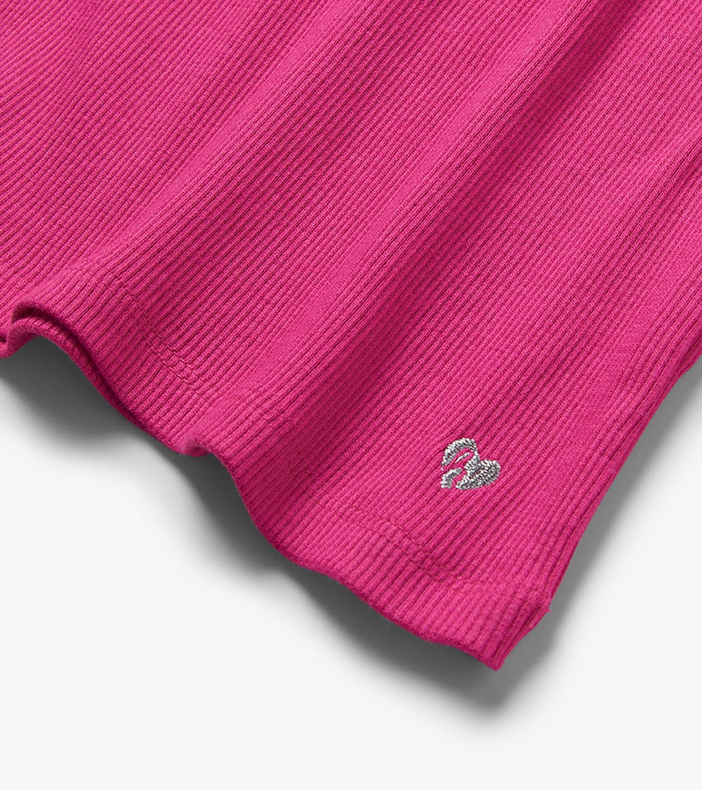 Close-up of a raspberry pink ribbed tank hem with small embroidered swan detail