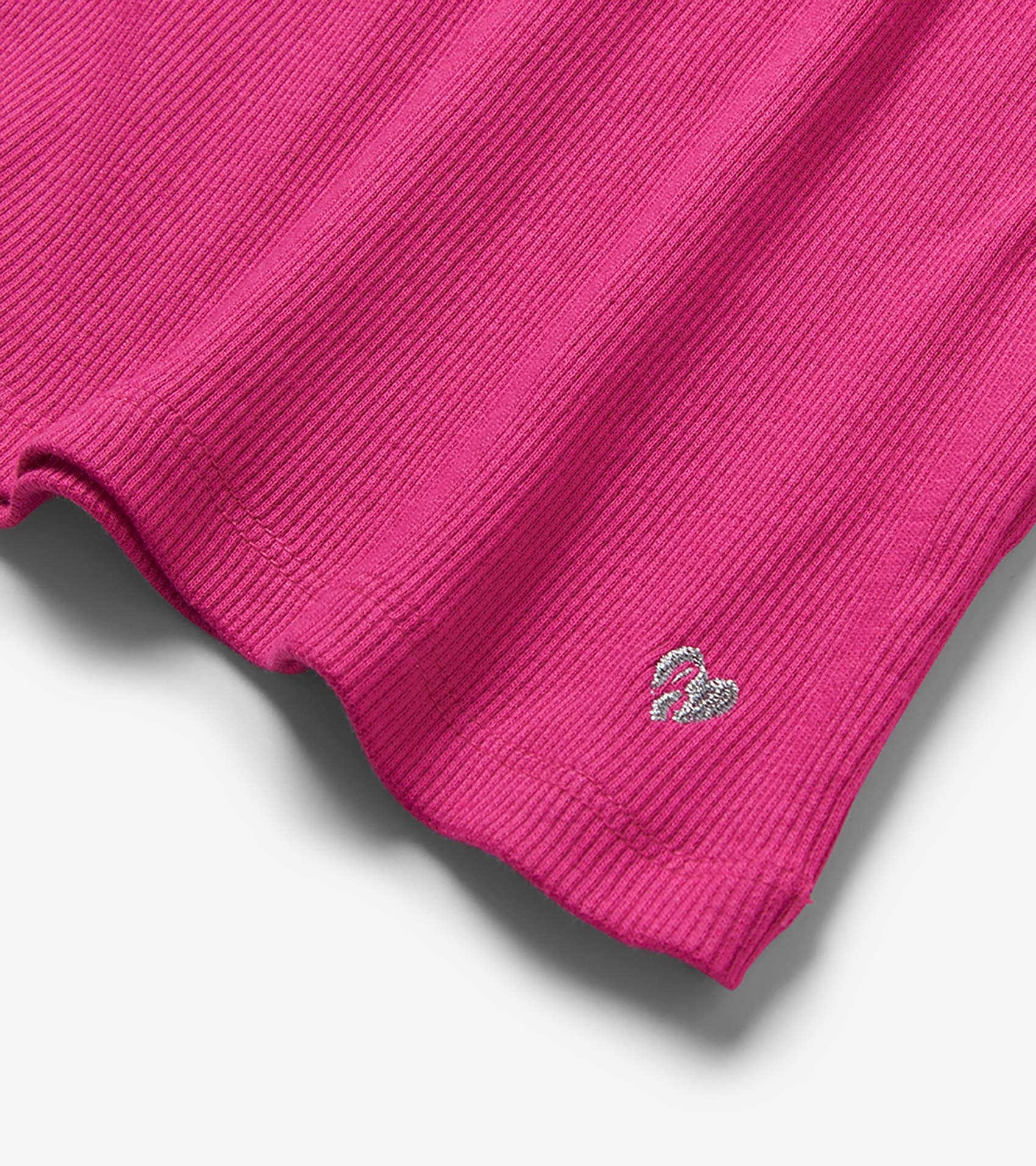 Close-up of a raspberry pink ribbed tank hem with small embroidered swan detail