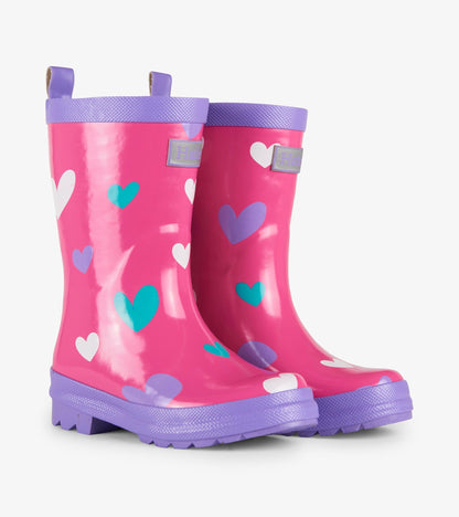 Pink waterproof wellies with colorful heart patterns and purple soles, designed for kids.