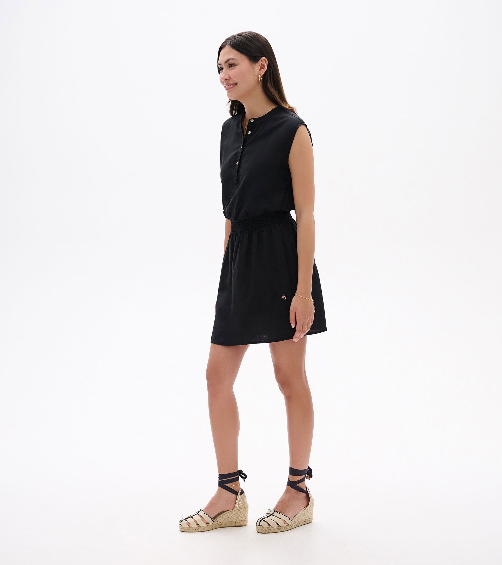 Black sleeveless dress with a buttoned collar and elastic waist, styled with espadrille wedges.