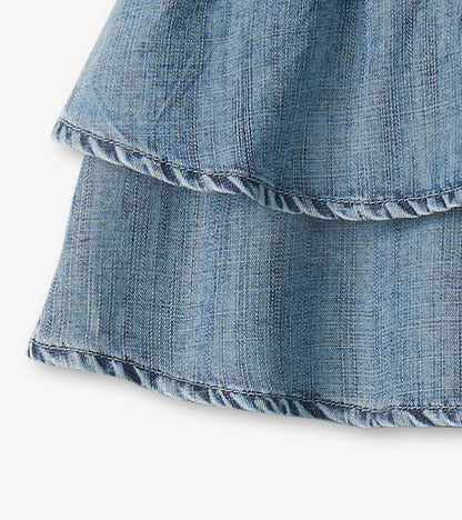 Blue denim girls skirt with layered ruffled hem and subtle plaid texture, close-up view