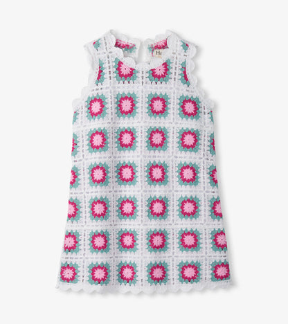 Sleeveless white crochet dress with pink and teal square floral pattern, scalloped hem, front view