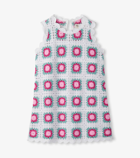 Sleeveless white crochet dress with pink and teal square floral pattern, scalloped hem, front view